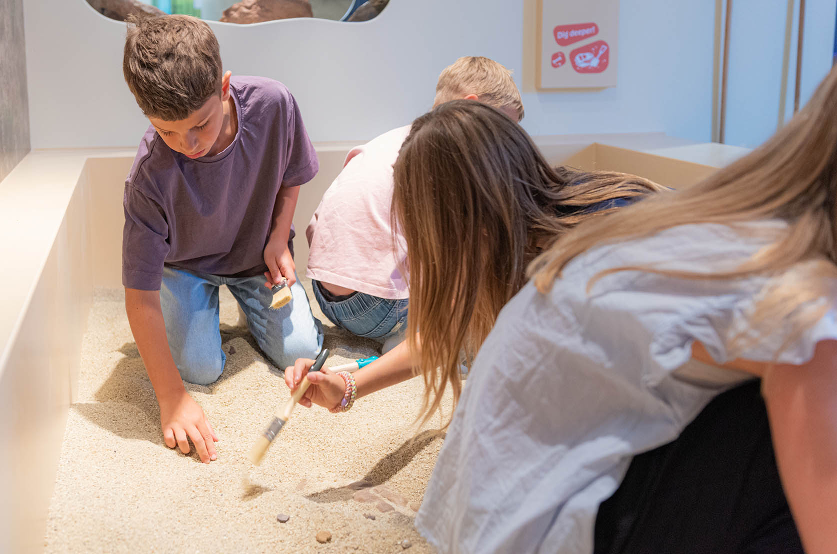Im Dino-Lab können alle selbst zu Forscherinnen und Forschern werden: Kinder graben im Sand nach Fossilien
